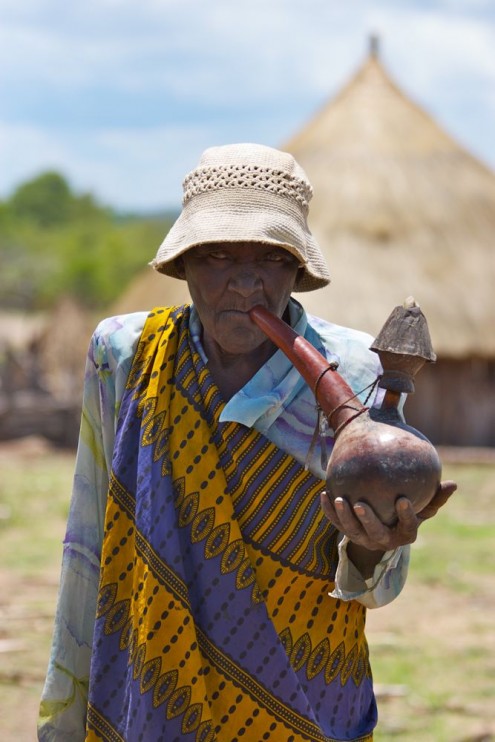 Old Tonga woman smoking water pipe, near Binga, Zimbabwe